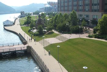 A park with a grassy area, a walkway, and a body of water. at LiveWell Apartments, Pittsburgh 15222